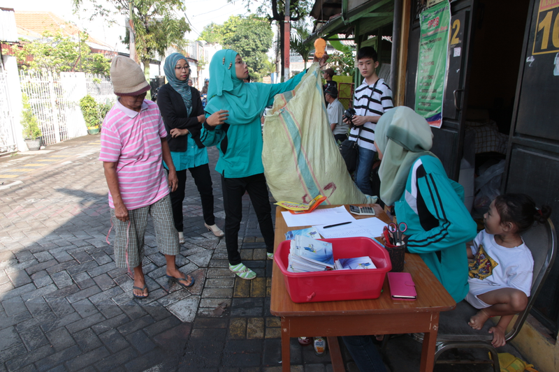 Employees of the Mulya Jaya Trash bank weigh a customer's deposits.